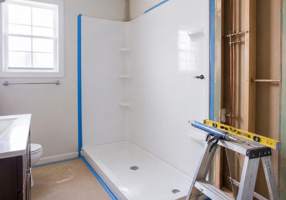 Bathroom mid-remodel with fresh subfloor and painter's tape